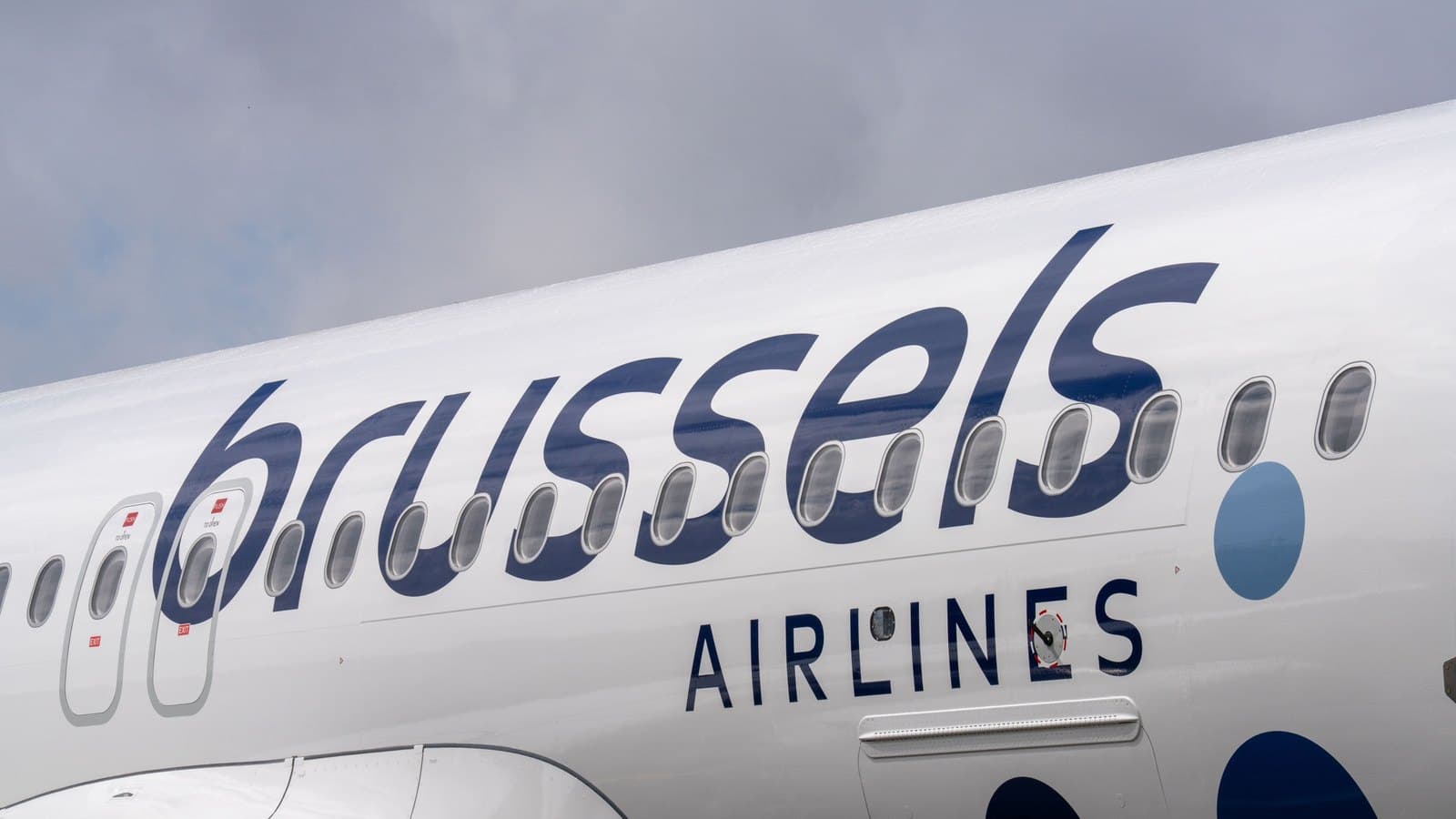 The forward fuselage of a Brussels Airlines aircraft under a grey sky, the carrier name running along the row of cabin windows.