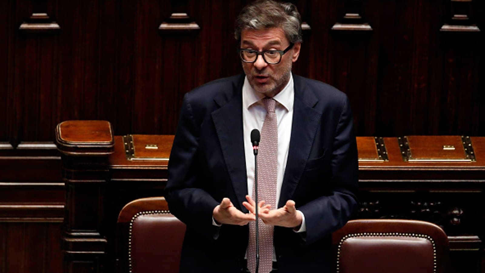 Italy's economy minister Giancarlo Giorgetti speaking and gesturing at a microphone in the Chamber of Deputies in Rome.