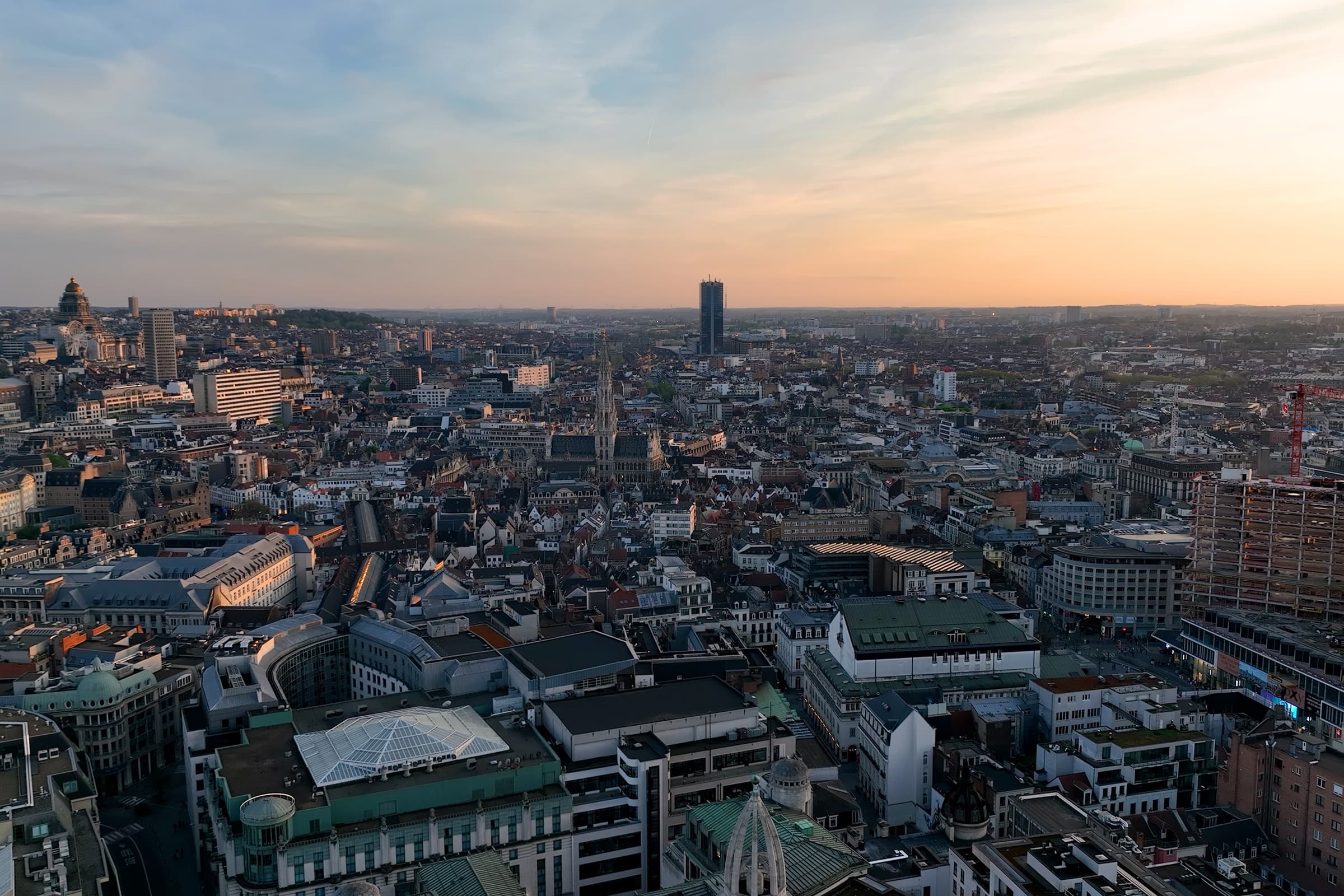 Aerial view of the Brussels skyline at sunset with the city hall spire visible among the rooftops