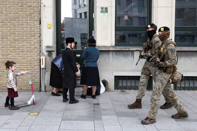 Armed soldiers on patrol on a Brussels street as residents go about their day