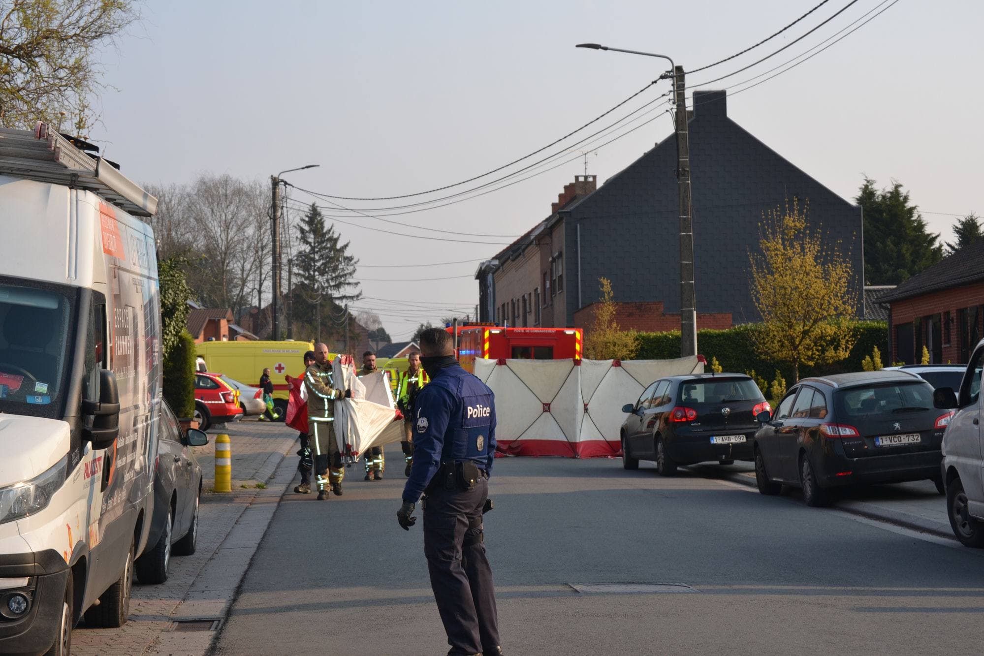 Police, firefighters and paramedics at the scene of an incident on a residential Belgian street, with vehicles cordoned off