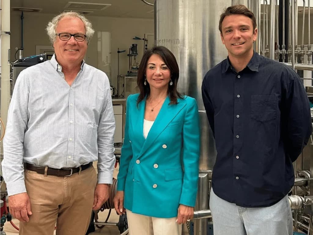 Three Maash executives standing in front of fermentation equipment at a production facility