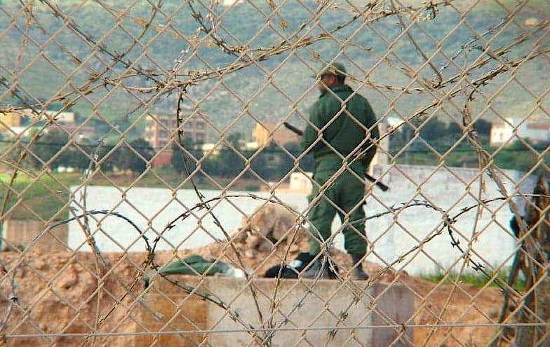 A guard seen through a razor wire border fence at the Ceuta enclave