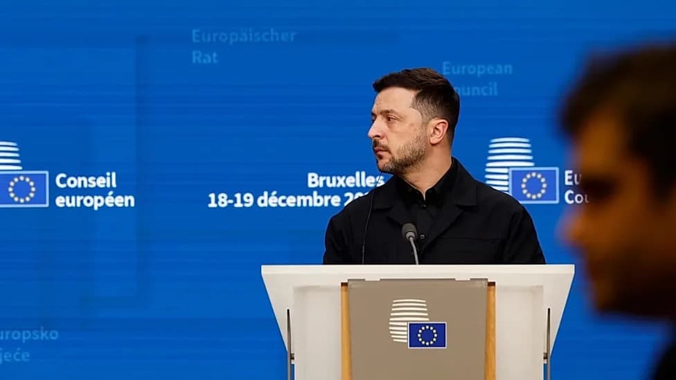 Ukrainian President Volodymyr Zelensky speaking at a podium at a European Council summit in Brussels