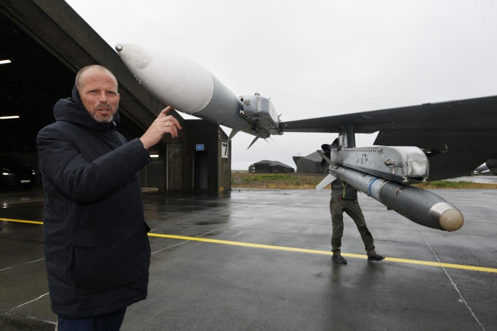 Defence Minister Theo Francken gesturing toward a missile mounted on a military aircraft during a base visit