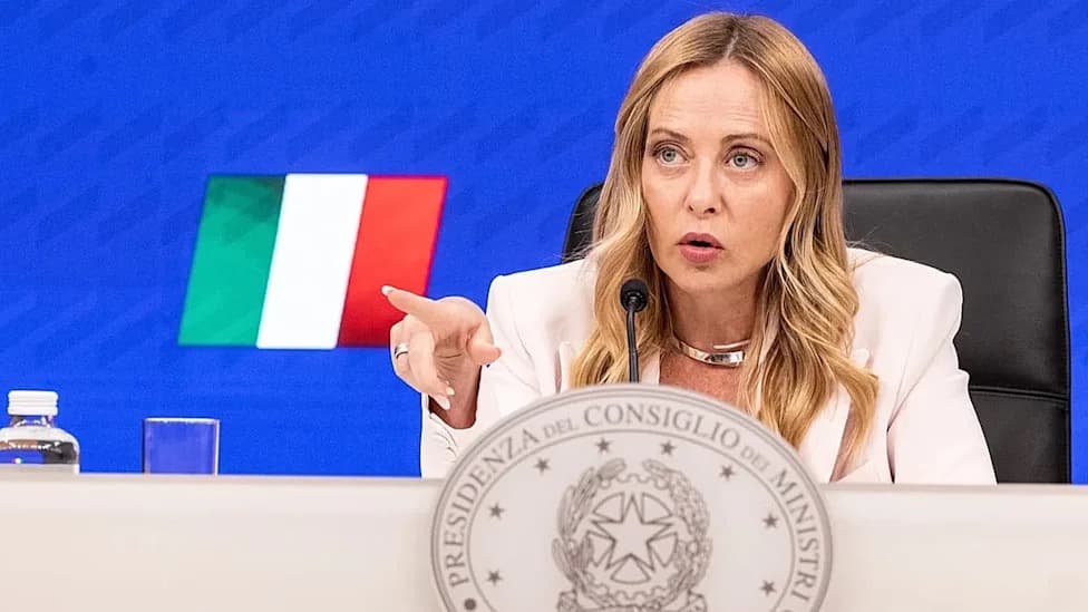 Italian Prime Minister Giorgia Meloni gesturing while speaking at a podium in front of the Italian flag